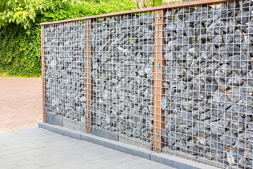 Natural garden separation with metal, wood and boulders. This photo was taken in the Netherlands where people like their privacy. By building a stone fence like this in their garden, It's clear where the border of your property is with this garden fencing.