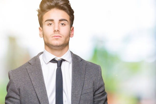 istock Young business man wearing suit and tie over isolated background with serious expression on face. Simple and natural looking at the camera. 1084059566