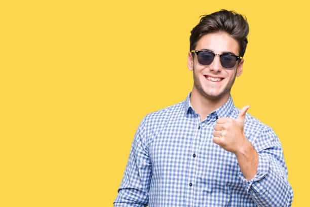 istock Young handsome man wearing sunglasses over isolated background doing ok gesture with hand smiling, eye looking through fingers with happy face. 1084060376