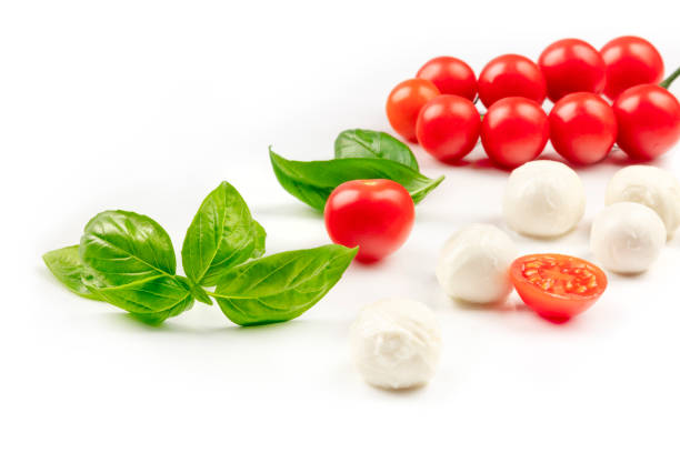 a photo of mozzarella cheese balls with fresh basil leaves and cherry tomatoes, the ingredients of the italian caprese salad, on a white background with a place for text - mozzarella cheese italy tomato imagens e fotografias de stock