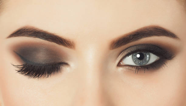 Beautiful woman with long eyelashes and with beautiful evening make-up. One eye is closed and the other is open. Beautiful woman with long eyelashes and with beautiful evening make-up. Eyes close up.One eye is closed and the other is open. eyebrow photos stock pictures, royalty-free photos & images