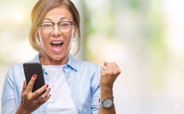 istock Middle age senior woman texting sending message using smartphone over isolated background screaming proud and celebrating victory and success very excited, cheering emotion 1084068842