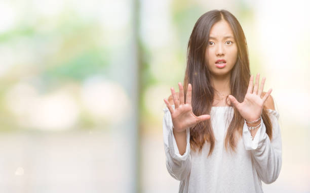 istock Young asian woman over isolated background afraid and terrified with fear expression stop gesture with hands, shouting in shock. Panic concept. 1084074876