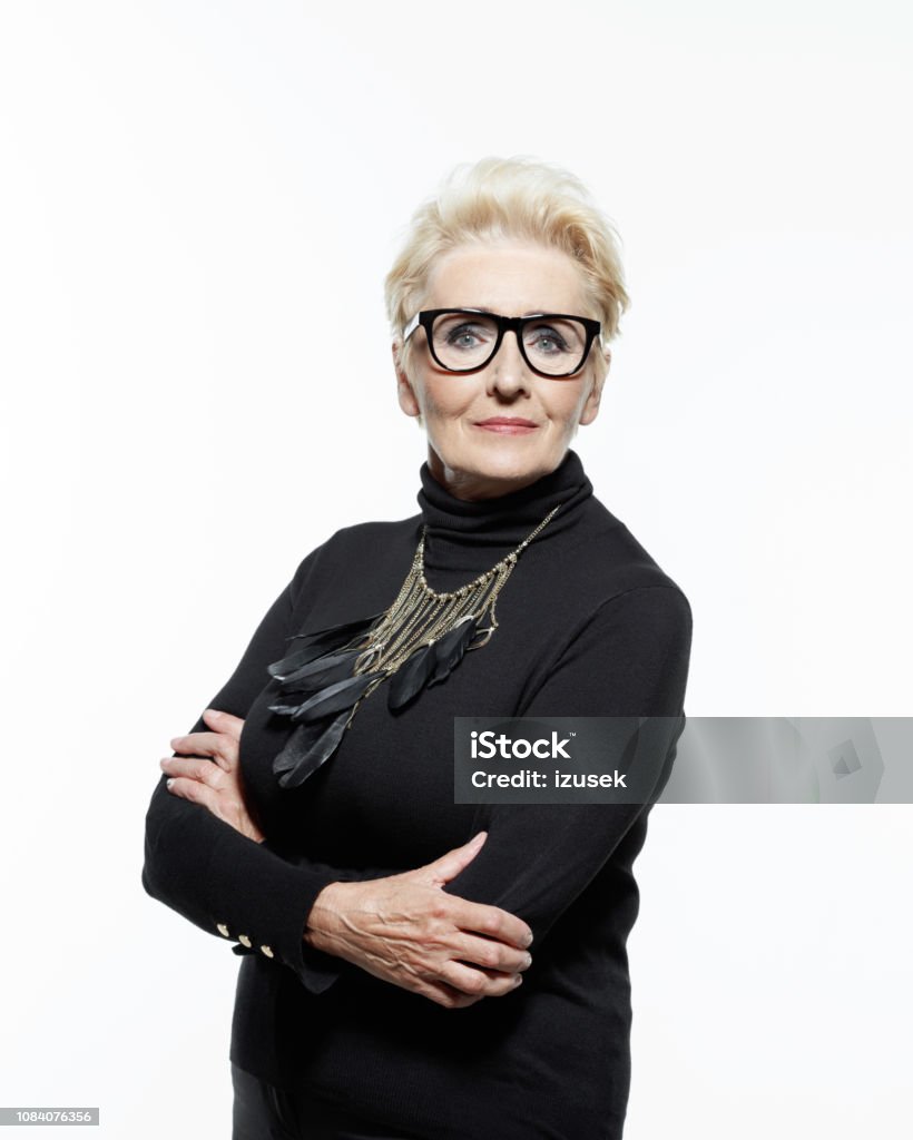 Portrait of elegant and confident senior woman Glamour portrait of beautiful confident senior woman, wearing black clothes, glasses and jewelry, looking at camera. Females Stock Photo