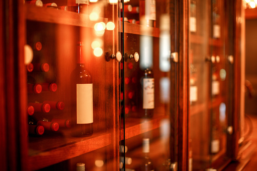Wine cubby with glass doors with wine bottles stacked within in a wine cellar.