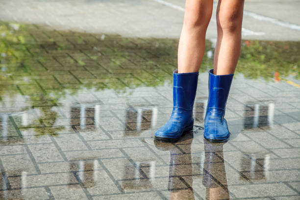 istock girl in rubber boots standing in a puddle after a rain 1084085516