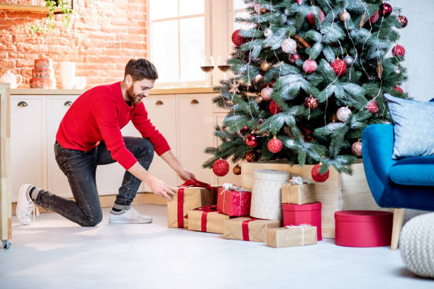 Man putting gifts under the New Year tree at home