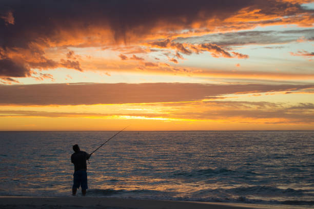 istock A man fishing on the beach at sunset 1084097796