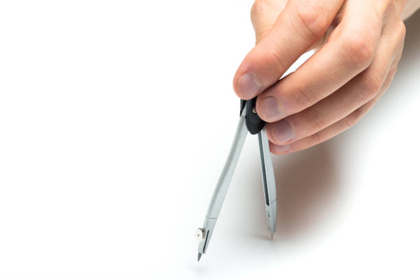 Human hand drawing a circle with a drawing compass. Fade to perfect white on the top of the image. Focus on the circle and the compass. Details of paper sheet still visible.