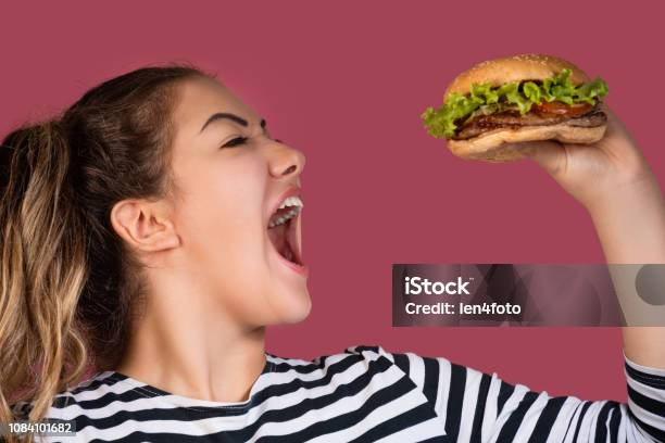 Hungry Cool Girl In Striped Tshirt Eating Hamburger Over Pink Background Stock Photo - Download Image Now
