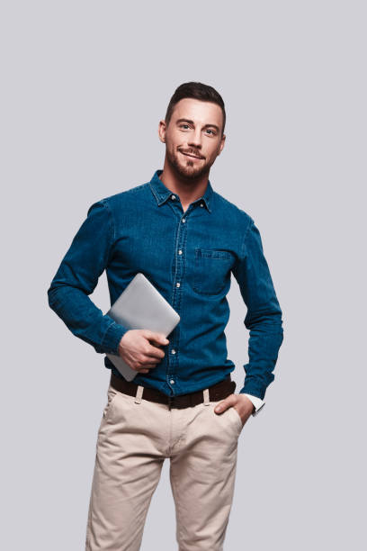 Confident businessmen. Good looking young man in smart casual wear looking at camera and smiling while standing against grey background preppy fashion stock pictures, royalty-free photos & images