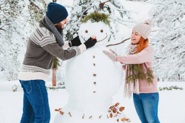istock Young couple making snowman in the park 1084103082