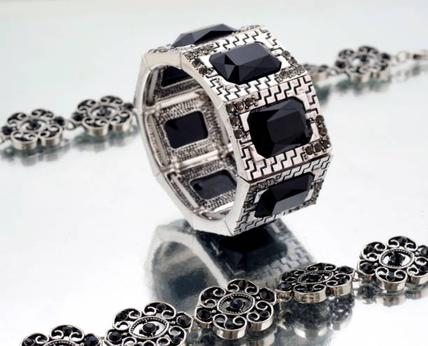 istock Silver bracelet with black gems on mirrorlike background 1084103786