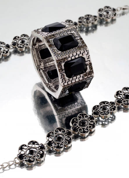 istock Silver bracelet with black gems on mirrorlike background 1084103794