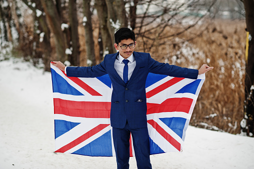 Stylish indian man in suit with Great Britain flag posed at winter day outdoor.