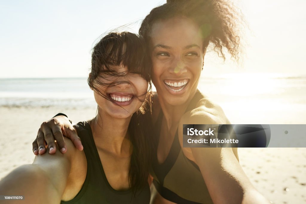 We can't help but feel great Cropped portrait of two attractive and athletic young women taking selfies while out for a run on the beach Friendship Stock Photo