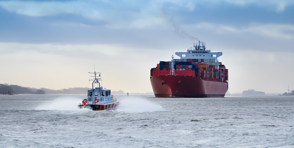 A small pilot boat in front of a huge container ship on the river Elbe, Germany