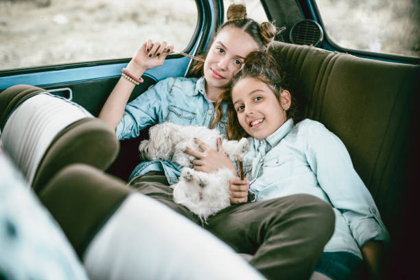 Cute Little Sisters Having Fun With Their Puppy On A Backseat