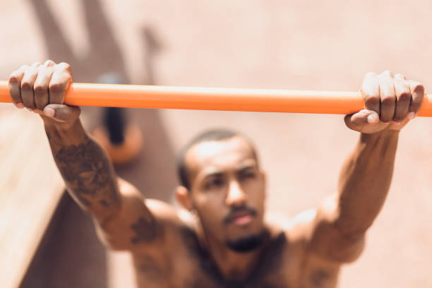 Male hands holding pull ups bar outdoors Male hands holding pull ups bar outdoors during workout chin ups photos stock pictures, royalty-free photos & images
