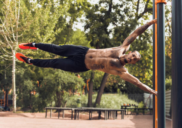 caber o homem fazendo push ups no ar livre barra paralela - muscular build men tattoo human arm - fotografias e filmes do acervo