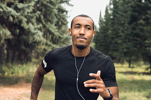 African-american man jogging and listening music at city park