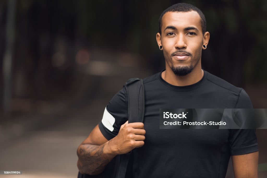 Muscular african-american man posing outside after workout Muscular african-american man wearing black t-shirt and backpack posing outside after workout Men Stock Photo