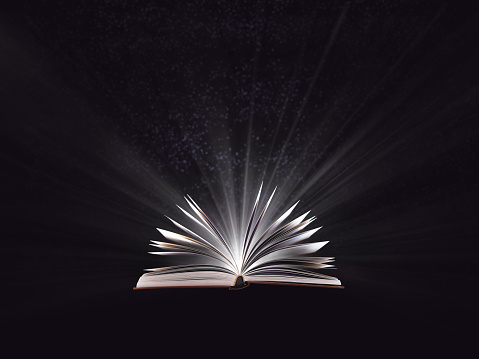 An open magic book, bewitched book glows in the darkness, magic light. Education. Dreamy image of a fairytale