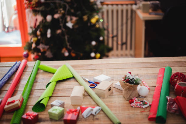 istock Small gift boxes with wrapping paper at table with Christmas tree in background 1084134892