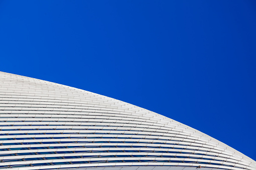 Abstract waving white metal architectural pattern on blue sky