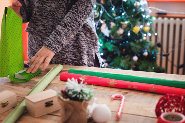 istock Small gift boxes with wrapping paper at table with Christmas tree in background 1084135454