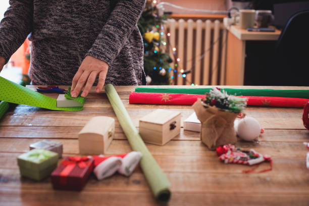 istock Small gift boxes with wrapping paper at table with Christmas tree in background 1084135792