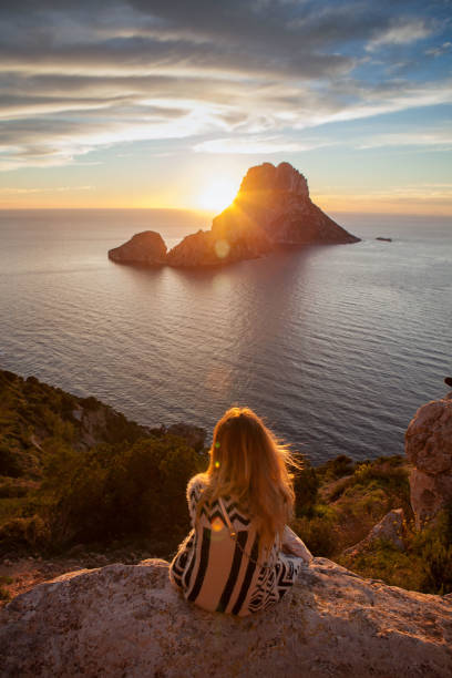 Donna di nuovo davanti a guardare un bellissimo tramonto in spiaggia. La spiaggia si chiama Es Vedra, a Ibiza e appartiene alle isole Baleari, in Spagna - foto stock