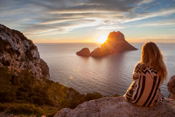 mulher volta para a frente a ver um belo pôr do sol na praia. a praia é chamada es vedra, em ibiza e pertence a ilhas baleares, espanha - ilha de ibiza - fotografias e filmes do acervo