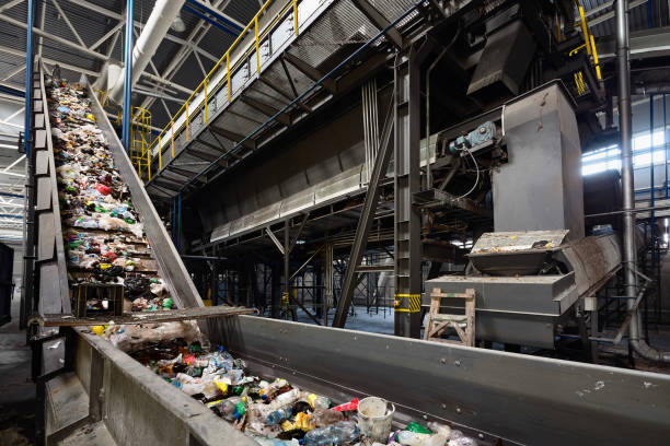 conveyor belt at recycling plant transports garbage inside drum filter or rotating cylindrical sieve with trommel or screen for sorting pieces of garbage into various sizes fractions - conveyor belt fotos imagens e fotografias de stock