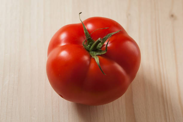 Side view of a ripe red organic heirloom tomato, isolated on white, copy space, horizontal aspect