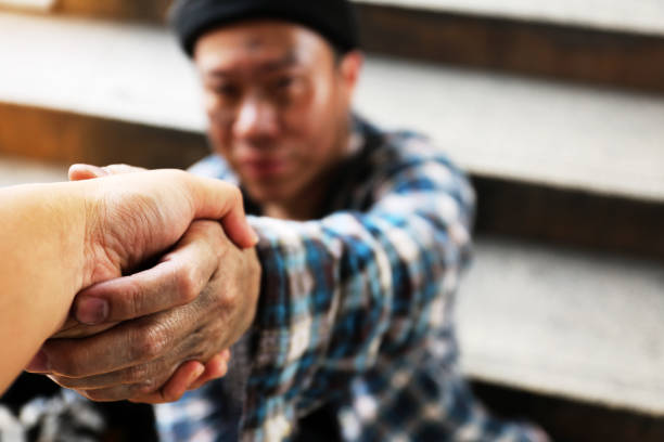 stretta di mano ravvicinata con un senzatetto sulla strada pedonale. - senzatetto foto e immagini stock