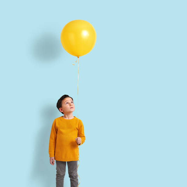 istock Cute child holding a yellow balloon 1084158318