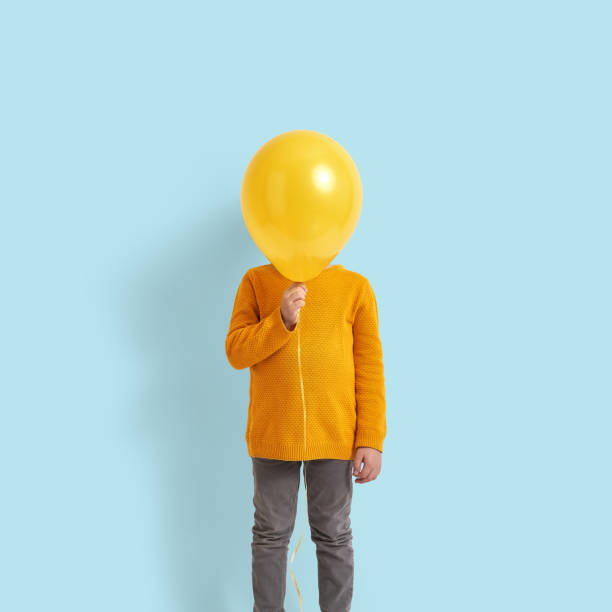 симпатичный ребенок, держащий желтый воздушный шар - balloon child elementary age people стоковые фото и изображения