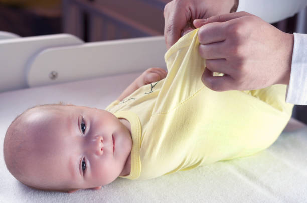 istock Young dad changes the diaper and clothes to his newborn small child. Selective focus. 1084161988