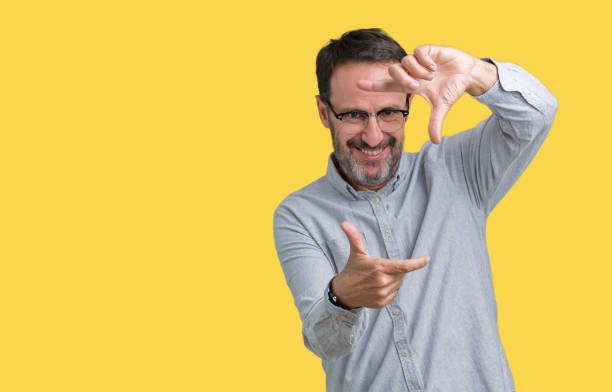 istock Handsome middle age elegant senior man wearing glasses over isolated background smiling making frame with hands and fingers with happy face. Creativity and photography concept. 1084164280