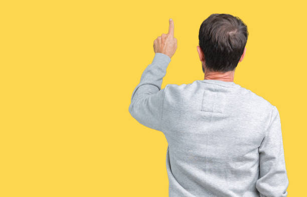 istock Handsome middle age senior man wearing a sweatshirt over isolated background Posing backwards pointing behind with finger hand 1084164594