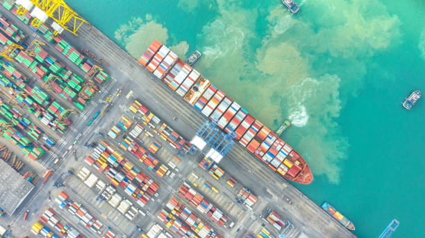 istock Container ship in export and import business logistics and transportation. Cargo and container box shipping to harbor by crane. Water transport International. Aerial view and top view. 1084170506