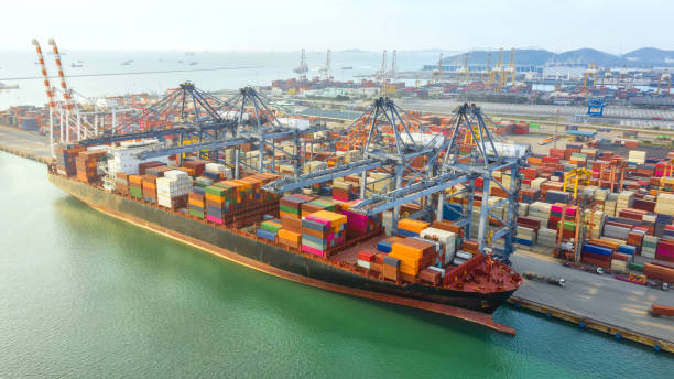 istock Container ship in export and import business logistics and transportation. Cargo and container box shipping to harbor by crane. Water transport International. Aerial view and top view. 1084170524