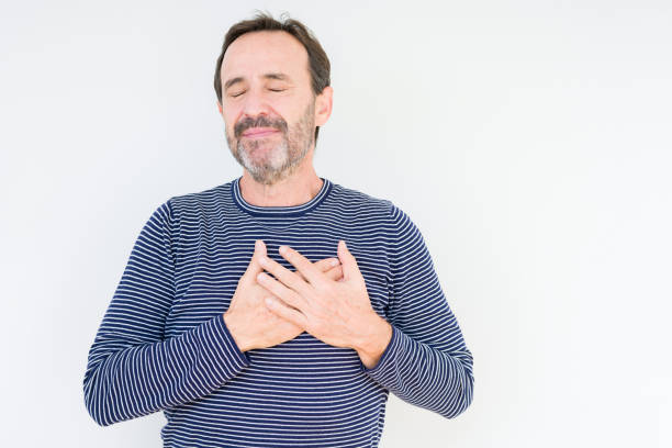 istock Handsome senior man over isolated background smiling with hands on chest with closed eyes and grateful gesture on face. Health concept. 1084171264