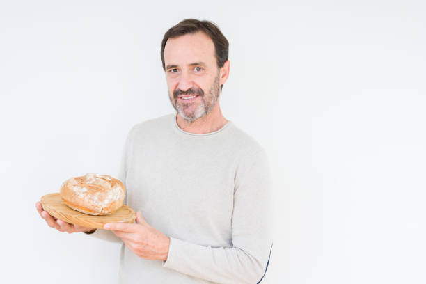 istock Senior man holding homemade fresh bread over isolated background with a confident expression on smart face thinking serious 1084171498