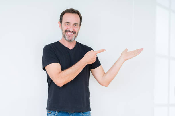 istock Senior man over isolated background amazed and smiling to the camera while presenting with hand and pointing with finger. 1084171864