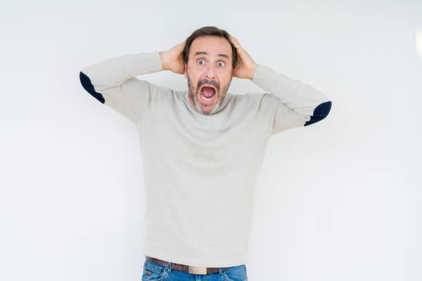 istock Elegant senior man over isolated background Crazy and scared with hands on head, afraid and surprised of shock with open mouth 1084172320