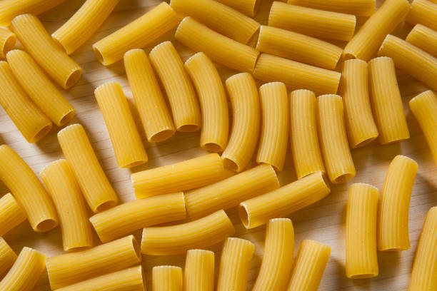istock Uncooked pasta Rigatoni on wooden background. Top view - Image 1084172426