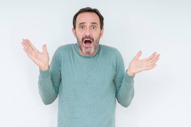 istock Senior man over isolated background clueless and confused expression with arms and hands raised. Doubt concept. 1084173770