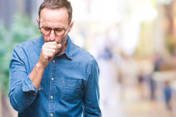 edad media hombre senior canoso con gafas sobre fondo aislado, sensación de malestar y tos como síntoma de resfriado o bronquitis. concepto de salud. - tosiendo fotografías e imágenes de stock
